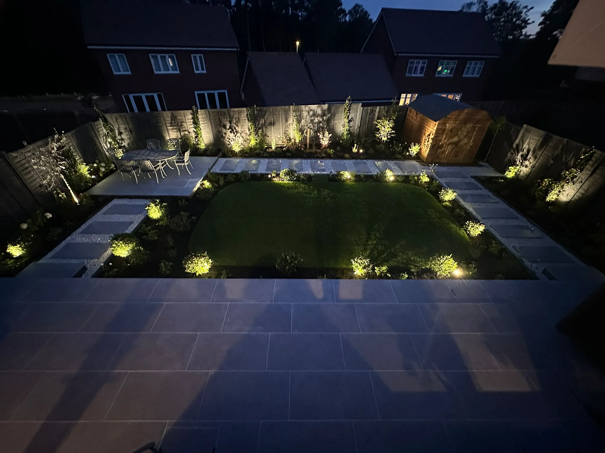 A backyard at night with lights on the lawn.