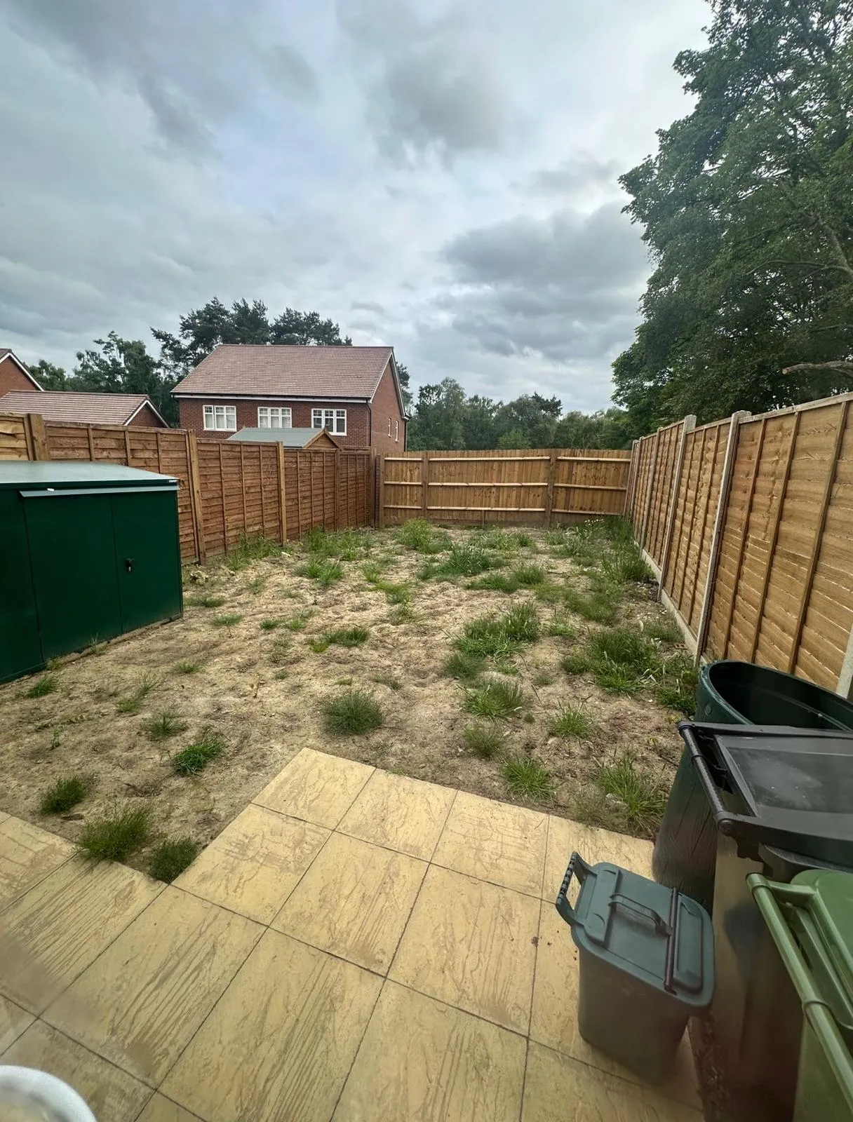 A back yard with a fence and trash cans.