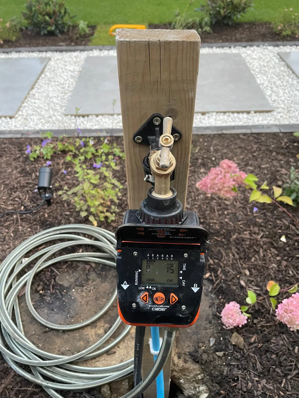 A meter attached to a wooden pole in a garden.