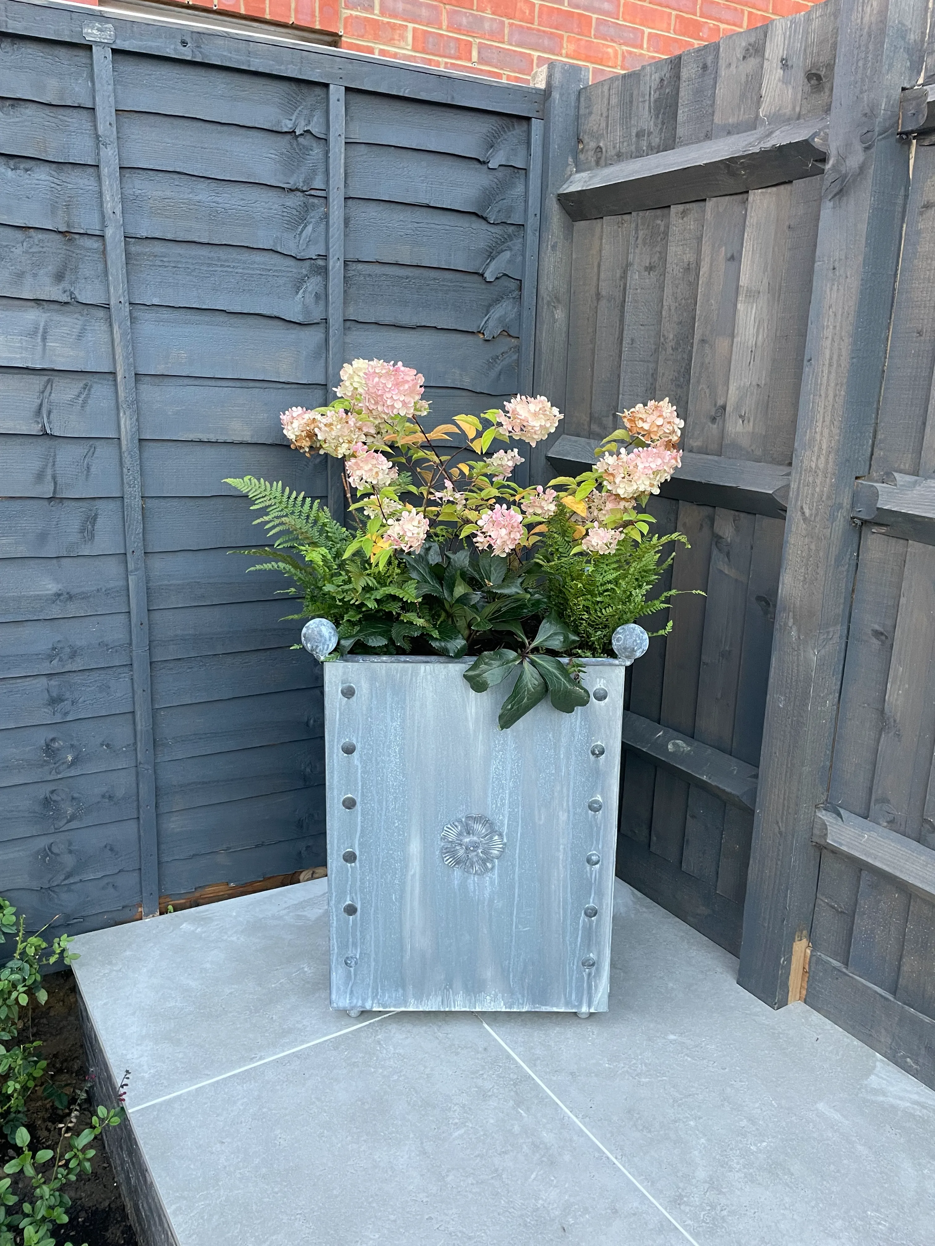 A planter with flowers in it sitting on a patio.